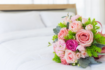 Very beautiful bouquet of flowers laid on a clean white bed.