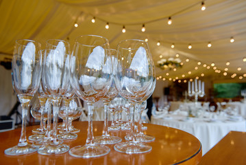 Sparkling glassware with wine and champagne on dinner table in restaurant, copy space. Crystal glasses ready for celebration. Wineglasses at luxury wedding reception