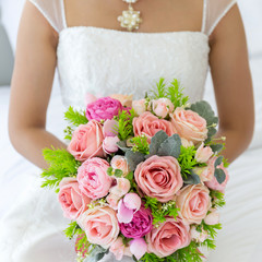 A beautiful bouquet of flowers in the bride's hand that is about to enter the wedding ceremony