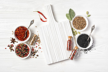 Different spices and seeds for tasty meals with white wooden board