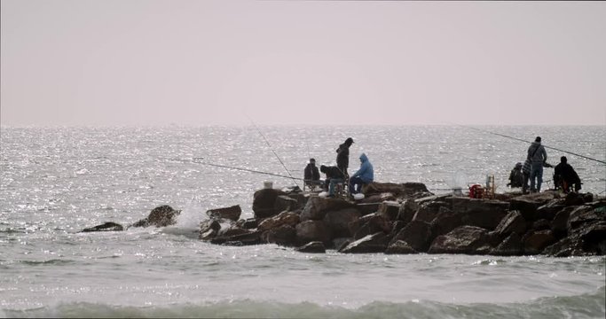 A group of fishermen in a breakwater fishing with rods