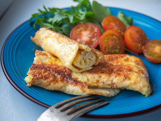 Homemade omelet with butter close-up on a blue plate. Fresh vegetables