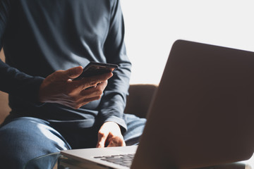 Man using mobile phone working on laptop computer