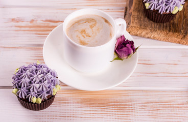 Chocolate delicious cupcake with cream and fragrant coffee with milk on a white wooden table.