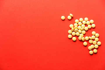 yellow round pills on red background as medical theme