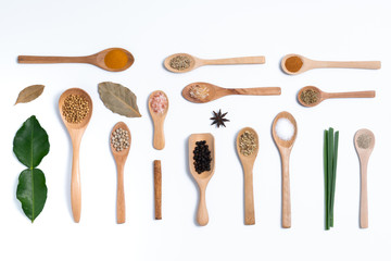 Various spices in wooden spoons, isolated background