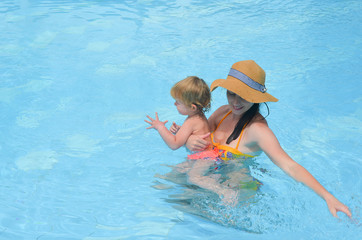 A young mother teaches her child to swim in the pool. Active fun vacation on a summer vacation lifestyle