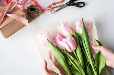 The orange bouquet of tulips is pink. Gift, wrapping paper, ribbons, scissors.