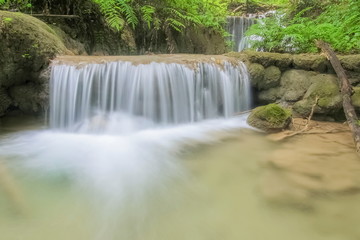 view of silky waterfall flowing on the rock around with green forest background, Pu Kaeng Waterfall, Doi Luang National Park, Chiang Rai, Northern of Thailand.