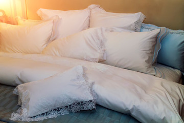 Close-up of new blanket with decorative white pillows in bedroom in sample model of hotel or apartment