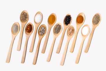 Various spices in wooden spoons, isolated background