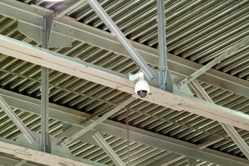 close-up view of a surveillance video camera attached to the joints of metal beams. strong iron construction made of channels that holds the roof