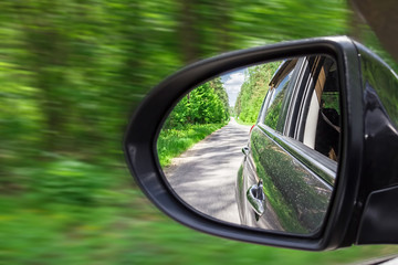 A view in the side view mirror. Mirror rear car. Reflection of the road