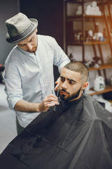 A man in a barbershop. Clipping beard in the barber. Rest in hairdressing salon