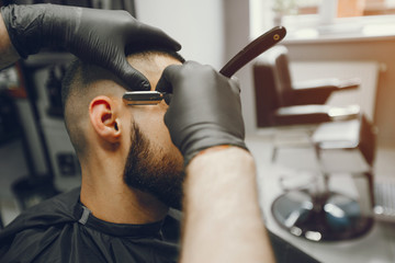 A man in a barbershop. Clipping beard in the barber. Rest in hairdressing salon