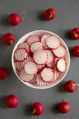 Fresh Radish Chips Slices in a white bowl on a concrete background, top view. Flat lay, overhead, from above.