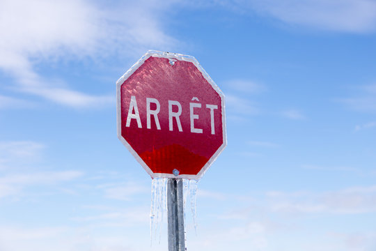 Horizontal low angle view of French stop sign encased in ice after ice storm seen during a late winter sunny morning, Quebec City, Quebec, Canada