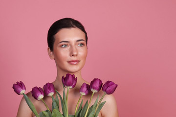 Portrait of a girl in the studio on a pink background, a girl with tulips on a pink background