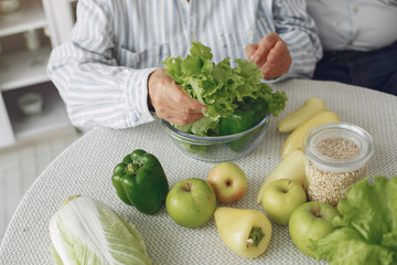 Couple in a kitchen. Grandparents sitting at home. Woman with vegetables