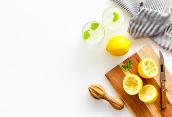 Obraz premium Homemade lemonade in glasses near juicer and cut lemons on white background top-down copy space