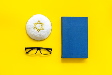 Jewish Kippah Yarmulkes hats with Star of David with Prayer book. Religion Judaisim symbols on yellow table. Top view, space for text