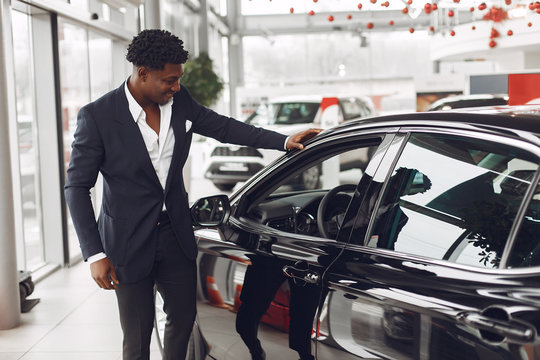 Man Buying The Car. Businessman In A Car Salon. Black Male In A Suit.