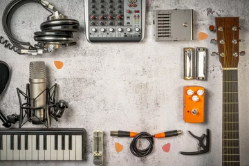 Tuinposter Singer-Songwriter and home recording, lifestyle music concept. Flat lay with musician and sound engineer stuff like guitar, mixer, microphone, keyboard, cables, headphones and so on. Vintage filtered © Lomb