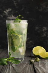 Non-alcoholic, cold mojito made from mint, sugar syrup, lime slices and soda, on a black background, a tasty and healthy drink to quench your thirst.