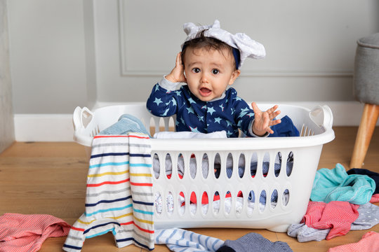 Funny baby sitting in laundry basket with underwear on head