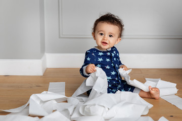 Cute baby making mess with toilet paper at home