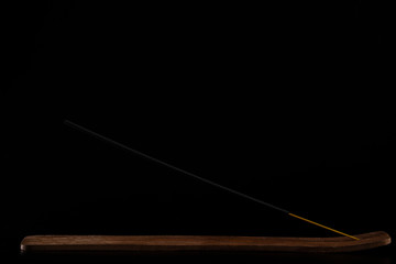 The aromatic stick in the stand on a black background. Incense for relaxation and meditation, Asian subject. Buddhism, natural flow and magic