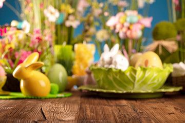 Happy Easter background. Bouquet of spring flowers. Easter decorations and Easter eggs in basket on rustic wooden table.