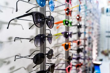 Row of luxury eyeglasses at an opticians store. Sunglasses on the stand.