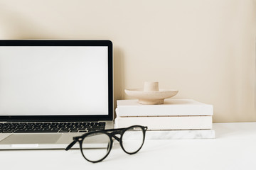 Blank screen laptop. Home office desk table workspace with glasses, notebook on beige background. Copy space mockup blog, website template. Blogger, outsourcing freelancer hero header.