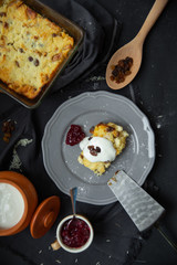 Cottage cheese casserole with raisins on a gray plate, poured sour cream on top. Flat lay, view from above. 