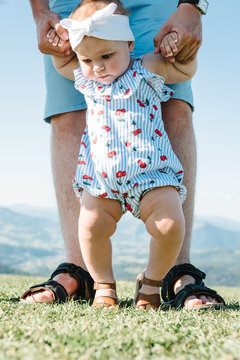 View on toddler. Father hold hands daughter enjoy nature and walk in the mountains. Young family spending time together on vacation, outdoors. The concept of family summer holiday.