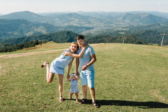 Mom, dad hold hands daughter in the mountains enjoy and look at nature. View down. Bottom view of legs. Young family spending time together on vacation, outdoors. The concept of family summer holiday.