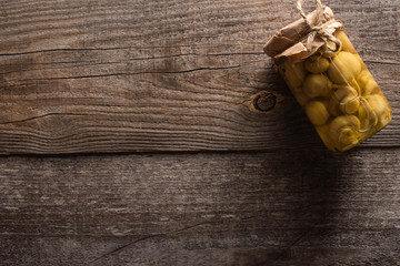 top view of homemade tasty pickled mushrooms in jar on wooden table