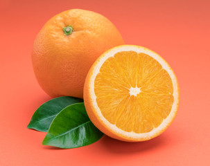 Orange fruit with orange slices and leaves isolated on orange background.