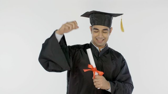 Attractive Indian graduate rejoicing on the day of convocation ceremony in India. Young graduated man in an academic dress is really happy and excited after receiving his college degree - white bac...
