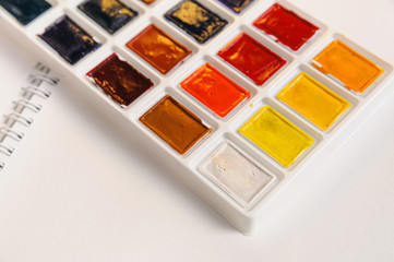 watercolour paints lying on a open white writing pad