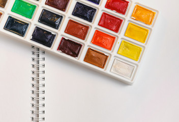 watercolour paints lying on a open white writing pad
