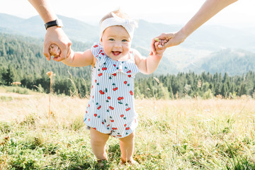 View on toddler. Mother, father hold hands daughter enjoy nature and walk in the mountains. Young...