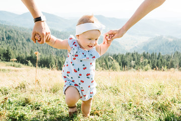 View on toddler. Mother, father hold hands daughter enjoy nature and walk in the mountains. Young...