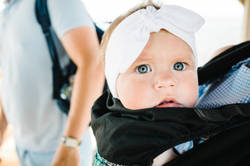 Carrying a baby. Young mother with her daughter in sling. Portrait of happy family. Mom, dad and...