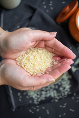 A scattering of rice, a handful of rice, rice in a metal bowl on a dark background. 