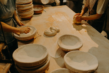 female hands in flour closeup kneading dough on table