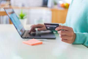 Close up of female hands holding a credit card and making a purchase using a laptop