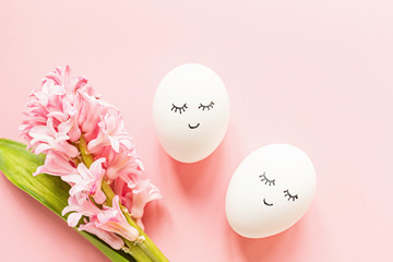 Creative easter eggs with cute face and sleepy eyes and hyacinth flower on pastel pink background. Happy Easter concept. Flat lay, top view, mockup, template, overhead, copy space