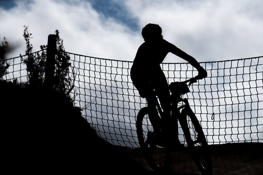 Mountain biker silhouette in a curve with net